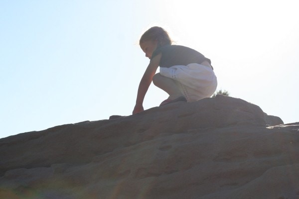 A girl on top of a big rock.