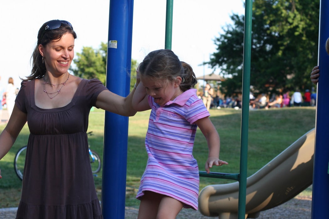 Kristen helping Zoe on the playground.