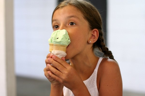 A girl eating a green ice cream cone.