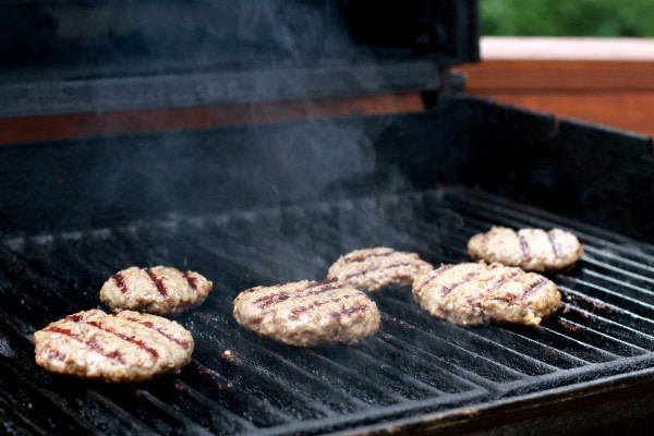 Hamburger patties on a gas grill grate.