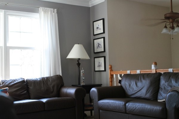 A living room with brown couches and gray walls, with a double window.
