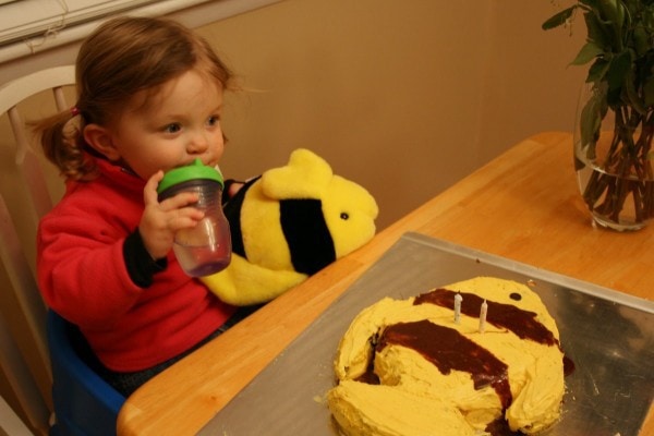 Toddler Zoe sitting in front of a striped fish birthday cake.