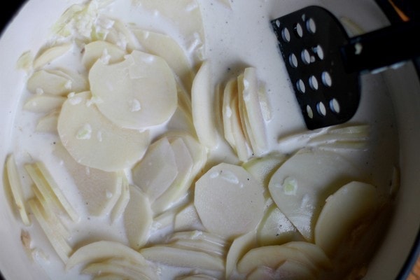 sliced potatoes in a pot of milk.