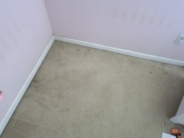 A dirty corner of carpet in a bedroom.