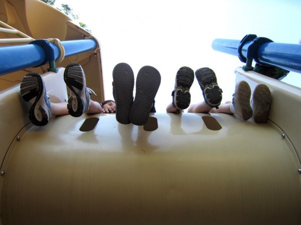 Children's feet hanging over a piece of playground equipment.