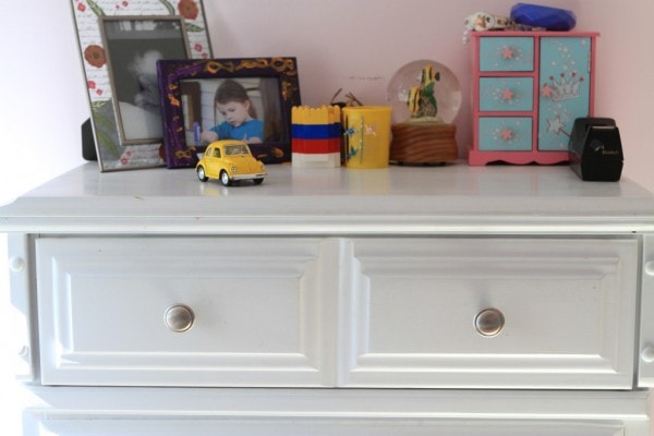 A white dresser with knicknacks on it.