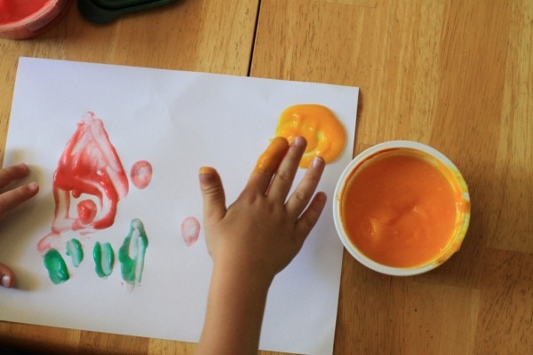 A child's hand using finger paint.