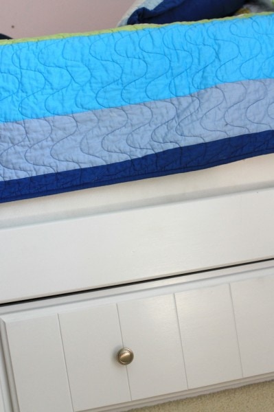 A white bed frame with drawers below.