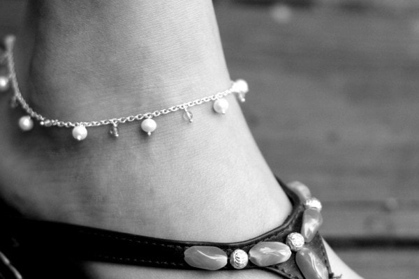 A black and white photo of a beaded anklet.