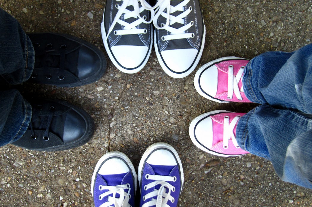 An overhead view of four children wearing Converse.