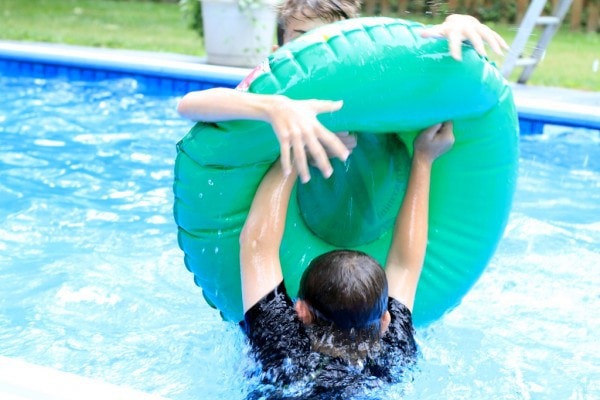 Children playing with a tube in a swimming pool.