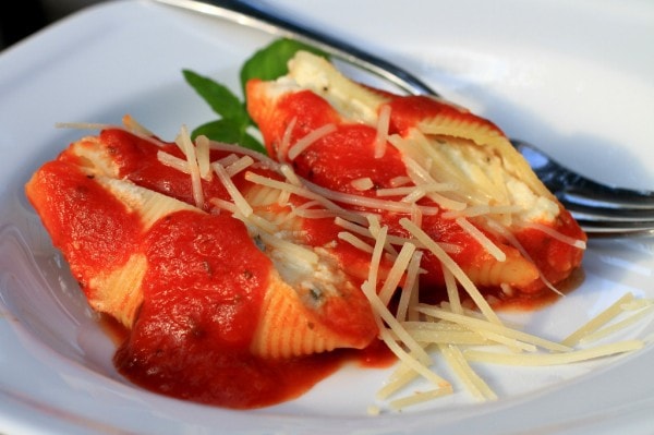 Two stuffed pasta shells on a white plate.