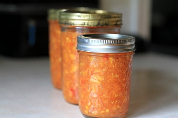 Three glass jars of peach jam.