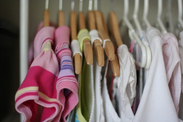 little girl dresses on wood hangers.