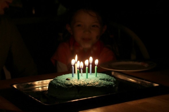A dark photo of lit birthday candles on top of a cake.