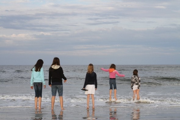 Children standing in a row on the beach.