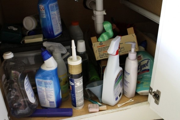 A cluttered under sink cabinet.