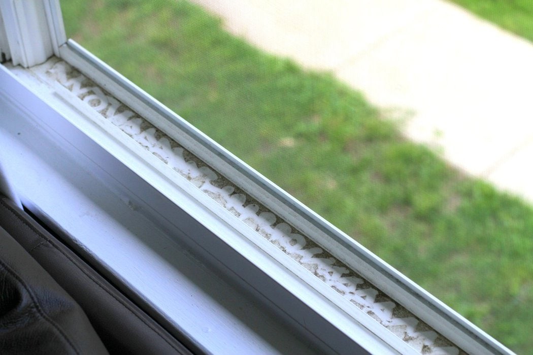 A dirty windowsill that a child has drawn in with their finger.