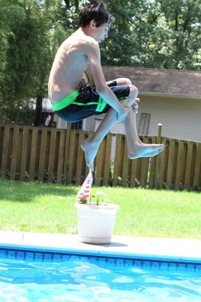 A kid doing a cannon ball into a pool.