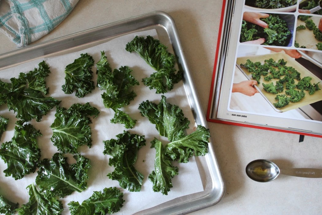 Kale on a cookie sheet to be made into kale chips.