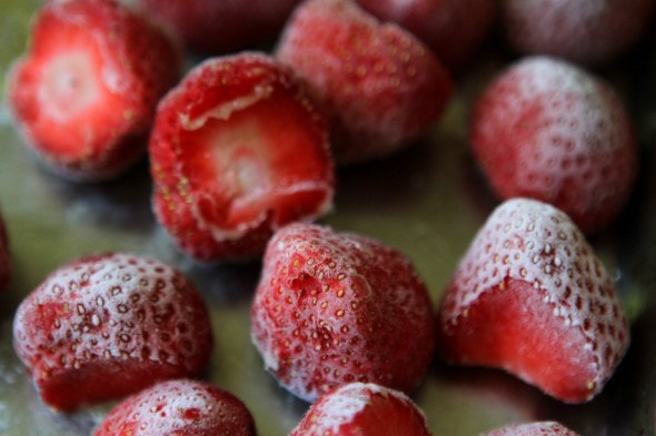 Frozen strawberries on a metal baking sheet.