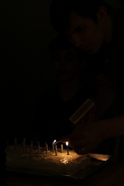 A dark photo of birthday candles, lit.