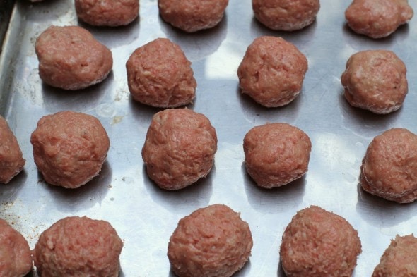 uncooked meatballs on a baking sheet.