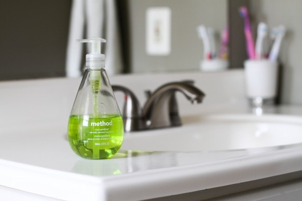 A bathroom sink with a green soap dispenser.