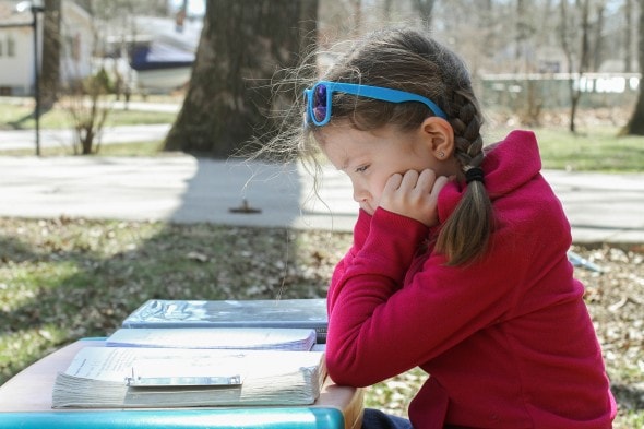 A girl doing math work at a picnic table.