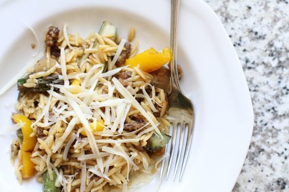 A bowl of orzo with sausage and veggies.