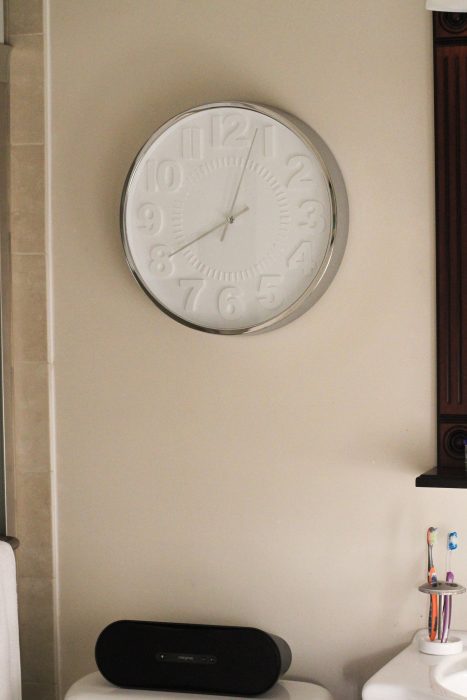 A bathroom wall with a clock.