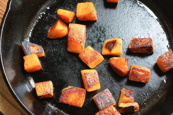 Browned butternut squash cubes in a cast iron skillet.