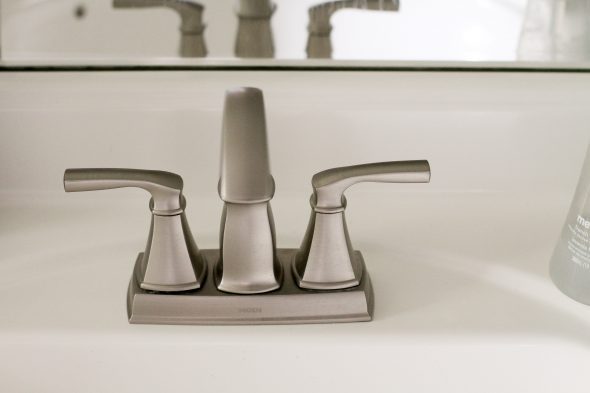 A silver Moen Hensley bathroom faucet on a white sink.