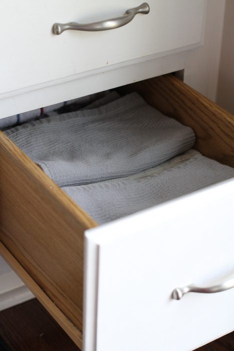 Gray kitchen towels in a painted white kitchen drawer.