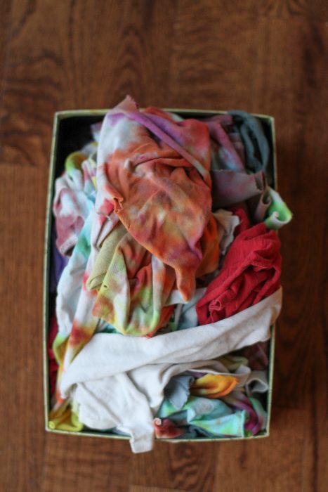 A box of tshirt rags on a wood floor.
