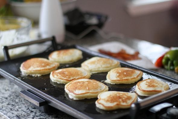 buttermilk pancakes cooking on an electric griddle.