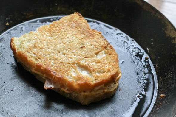 Half a panini in a black skillet.