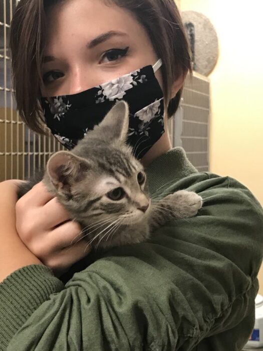 Zoe, wearing a flowered cloth mask, holding a rescue cat