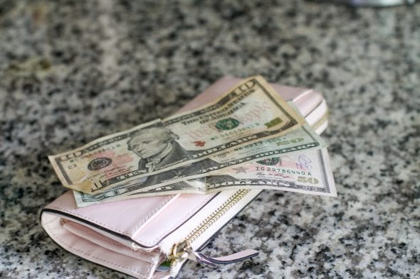 cash on top of a pink Kate Spade wallet