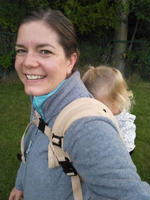 Ruth T with a baby in a back carrier.