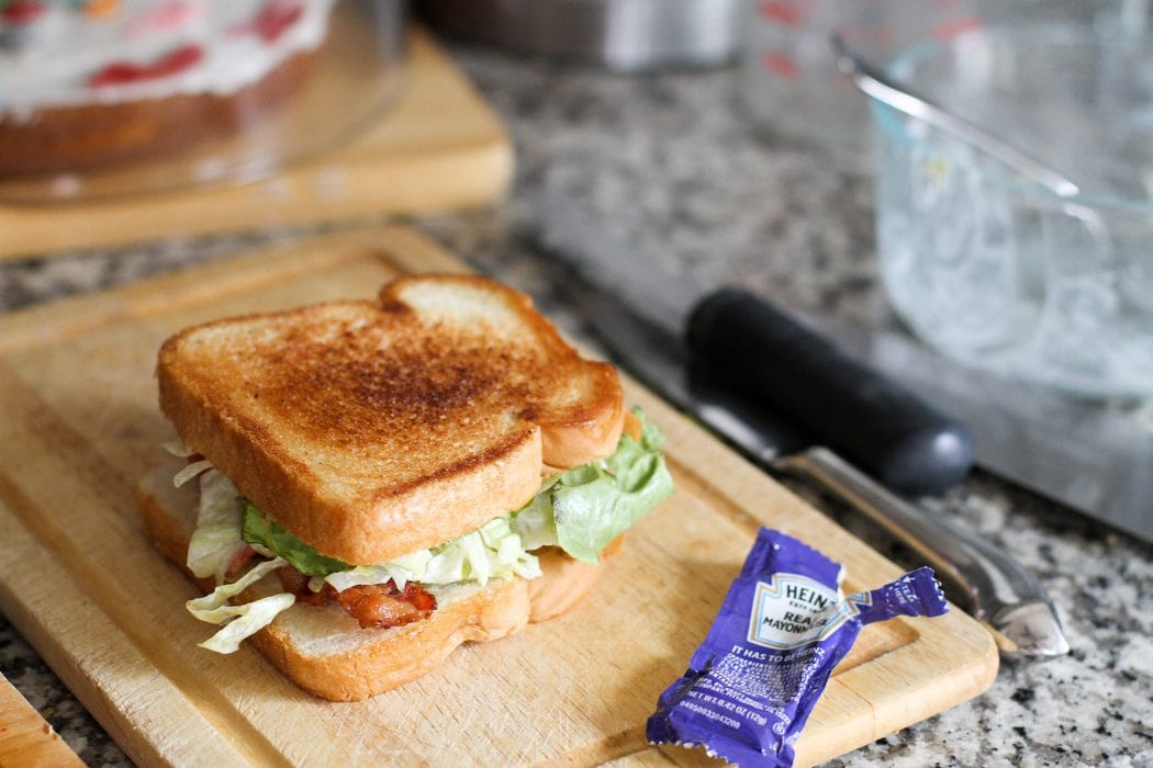A grilled BLT sandwich, on a wooden cutting board.