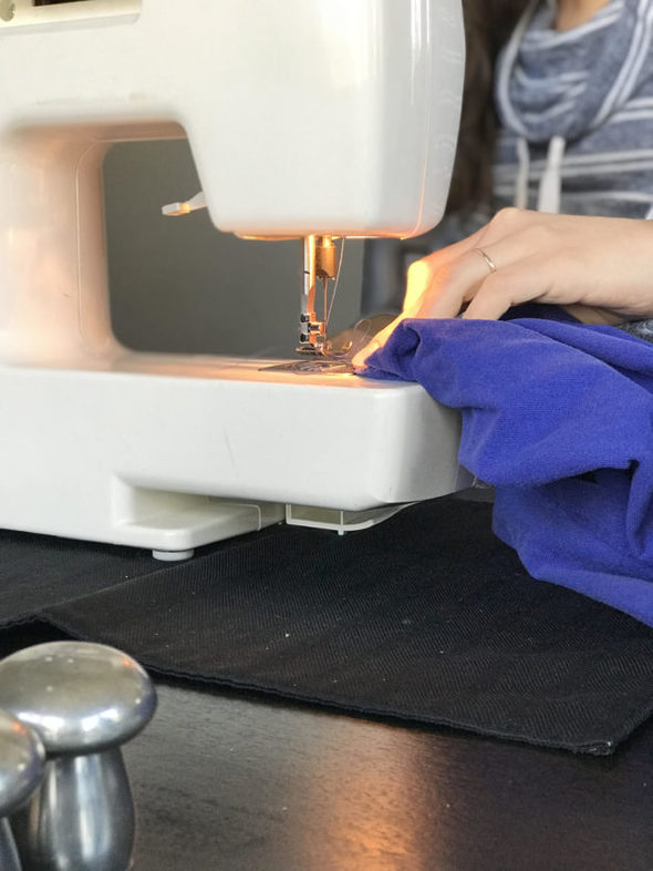 Kristen's hands doing mending with her sewing machine.