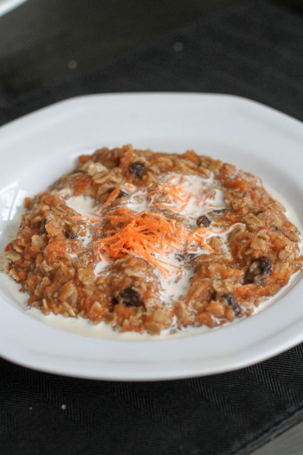 White bowl of oatmeal with carrots.