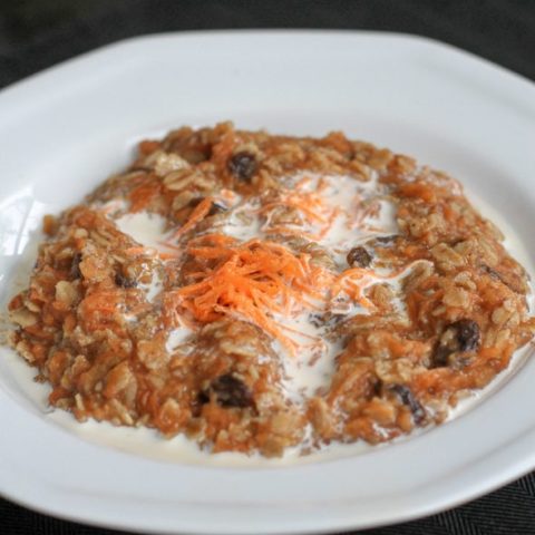 White bowl of oatmeal with carrots.