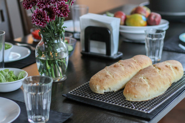 French bread loaves on a table with salad.