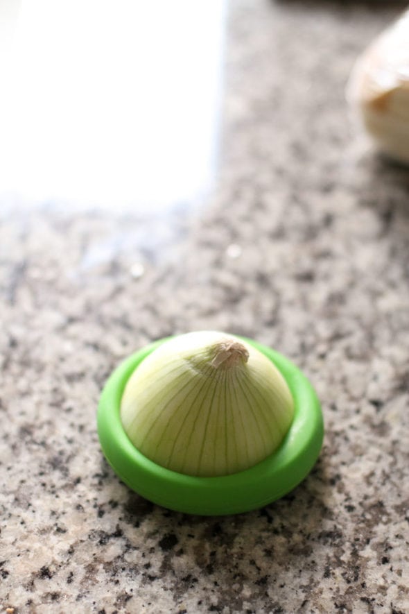 Onion with a green Food Hugger lid on the cut end.