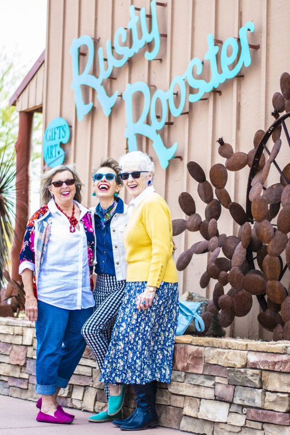 Three ladies with sunglasses on in front of a restaurant.