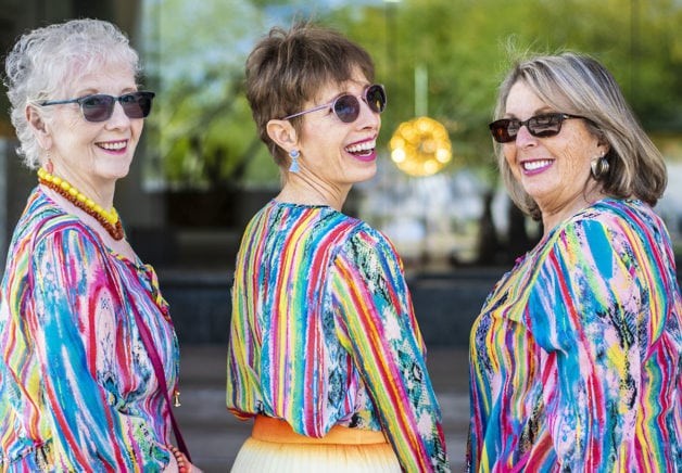 Three middle aged ladies in colorful striped shirts.