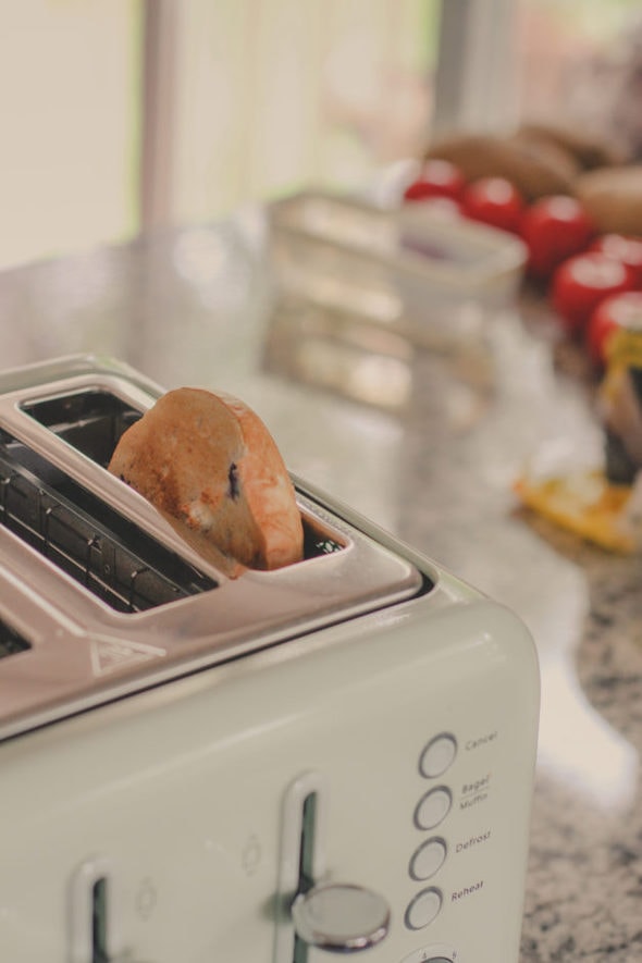 A bagel half in a light green toaster.