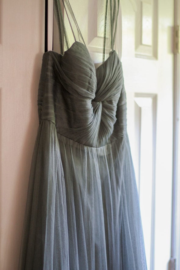 sage green bridesmaid dress hanging in a doorway.